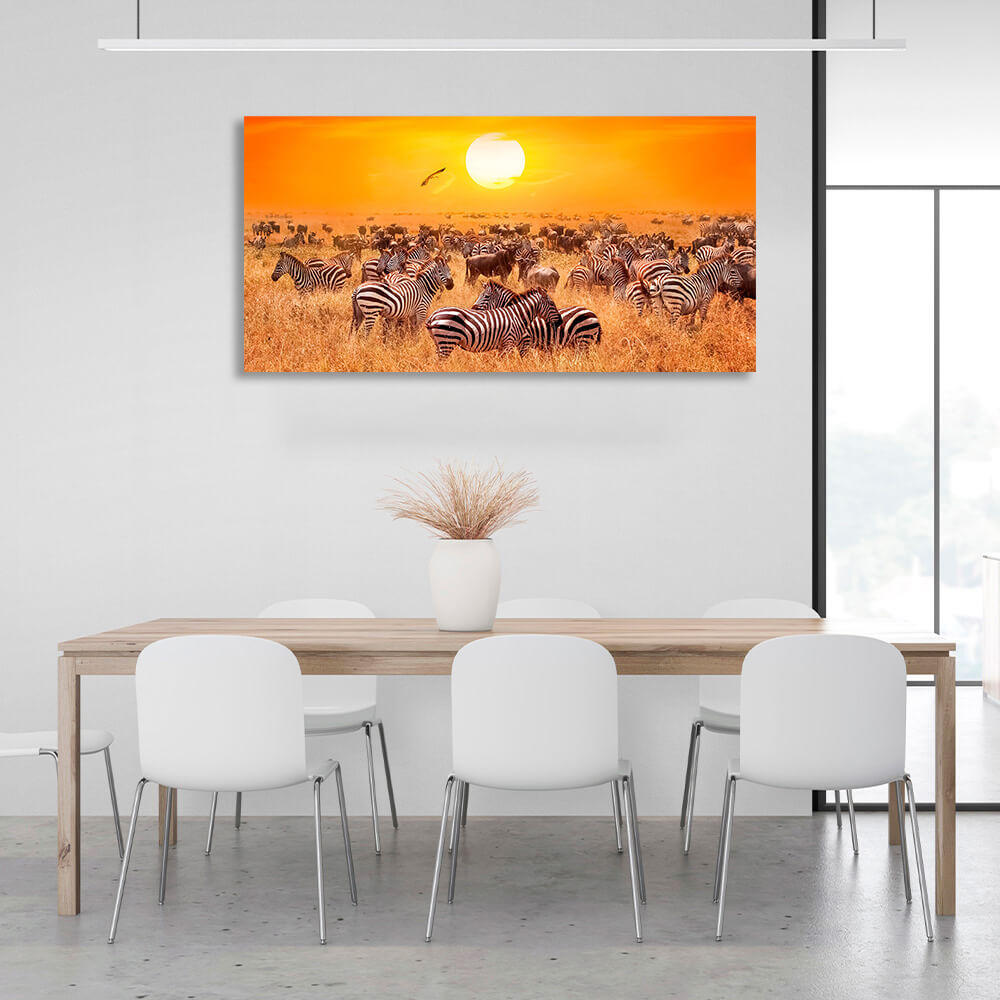 Riesige Herde Zebras auf einer trockenen Weide vor dem Hintergrund des Sonnenuntergangs. Kunstdruck auf Leinwand.